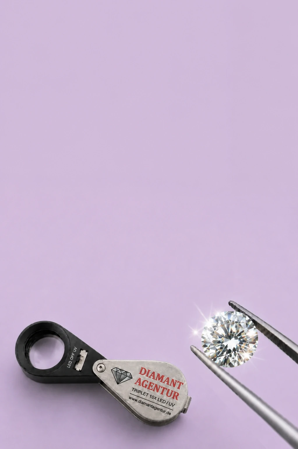 Diamant in einer Pinzette neben einer Prüflupe der Diamant Agentur